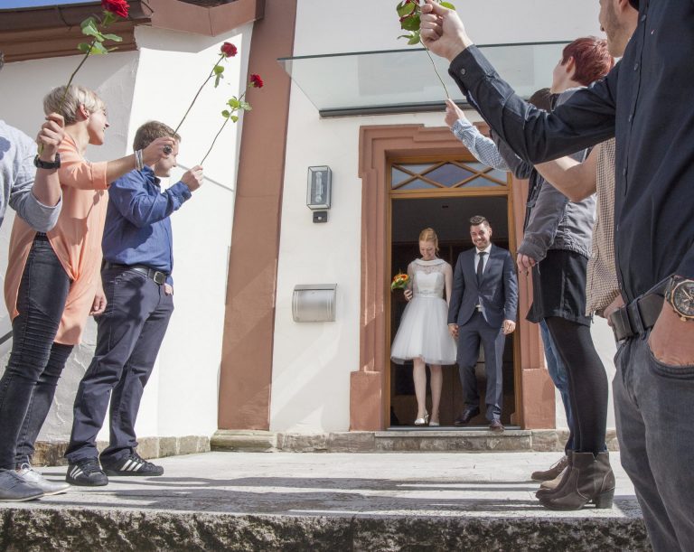 Bild: Hochzeitspaar läuft durch ein stehendes Spalier, symbolisiert traditionelle Hochzeitsbräuche und Glückwünsche der Gäste.